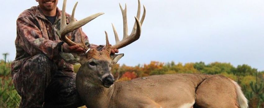 Adam Hupf smiles behind his new state record deer.